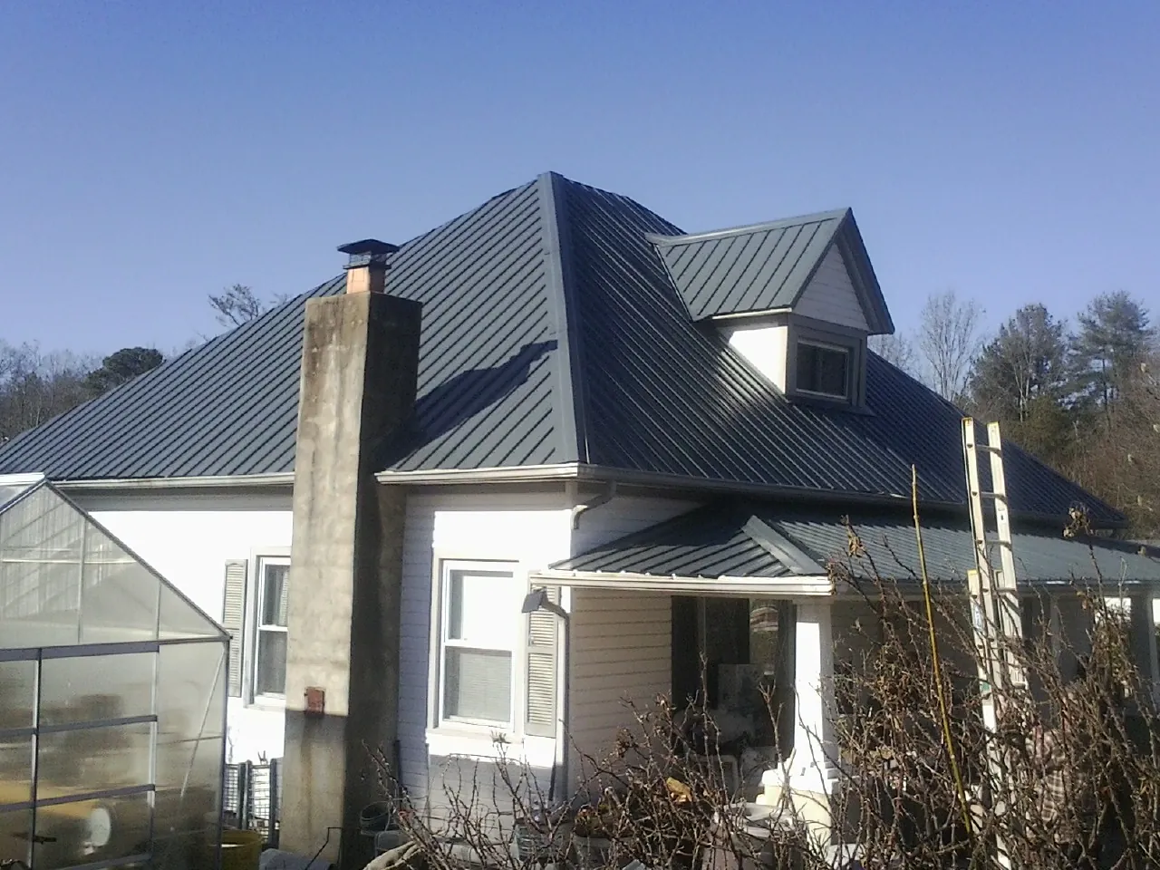 Dark blue standing seam metal roof on a white farmhouse with dormer — Slate & Tile Roof Repair by Roofing Brothers in Grangeville