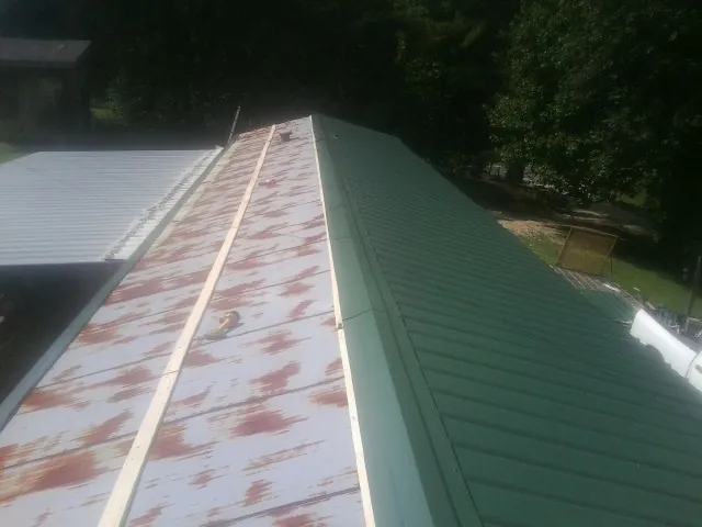 Old rusted panels beside newly installed green metal roofing — Wind Damage Roof Repair by Roofing Brothers in Grangeville