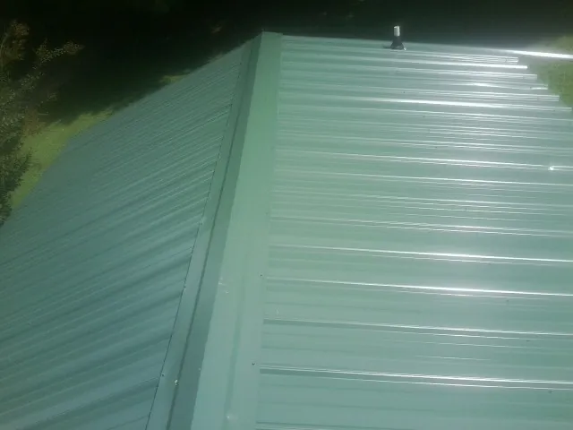 New green metal panels meeting at the ridge of a roof — Flat Roof Repair work by our crew in Grangeville