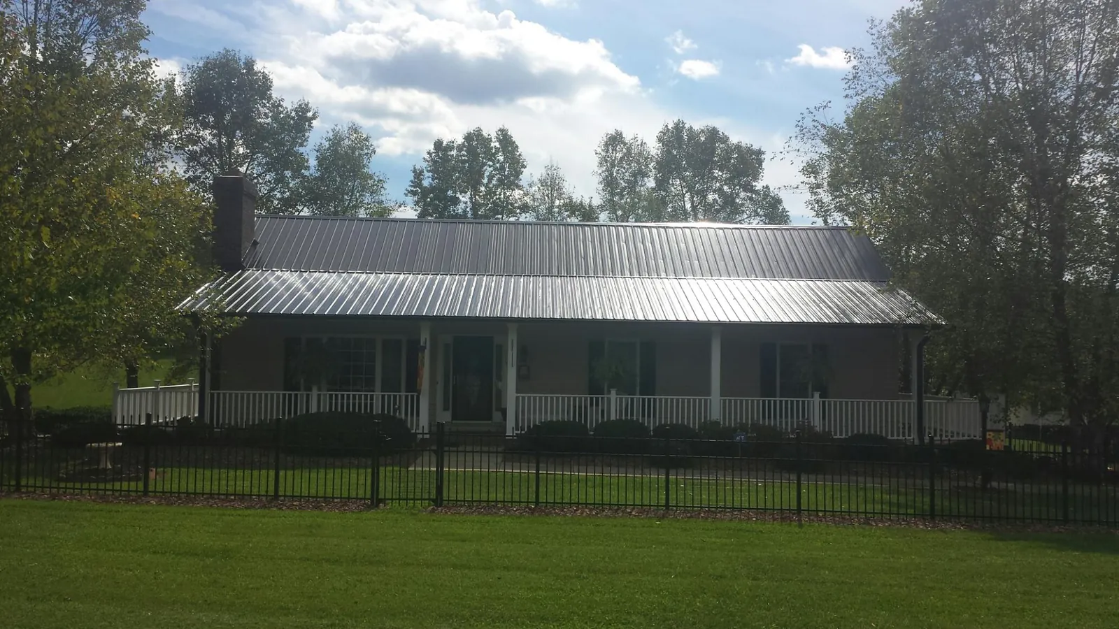 Gray metal roof on a brick ranch with a full width front porch — Gutter Guard Installation work by our crew in Grangeville